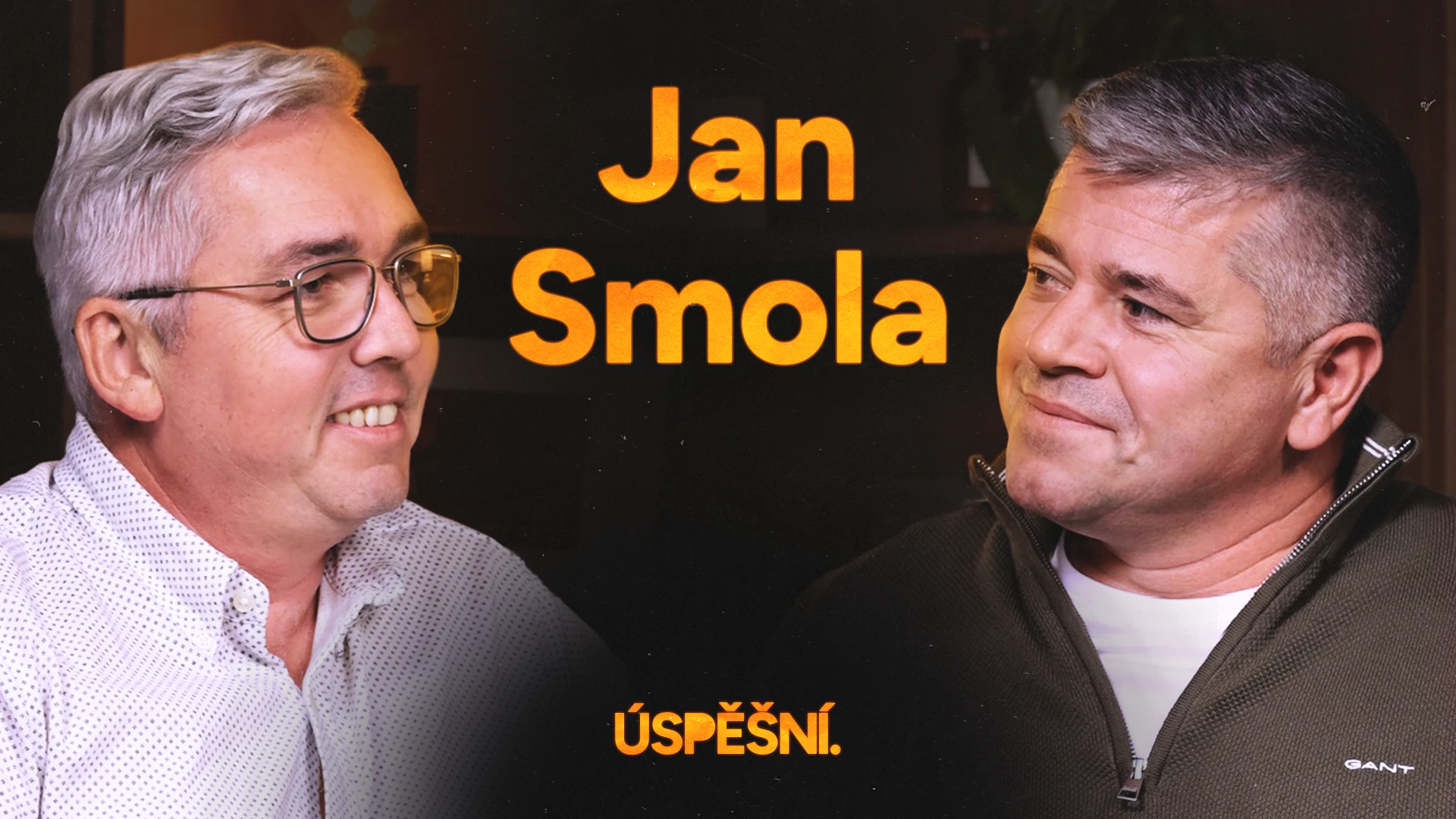 Muž v košili a brýlích sedící v křesle v podcastovém studiu